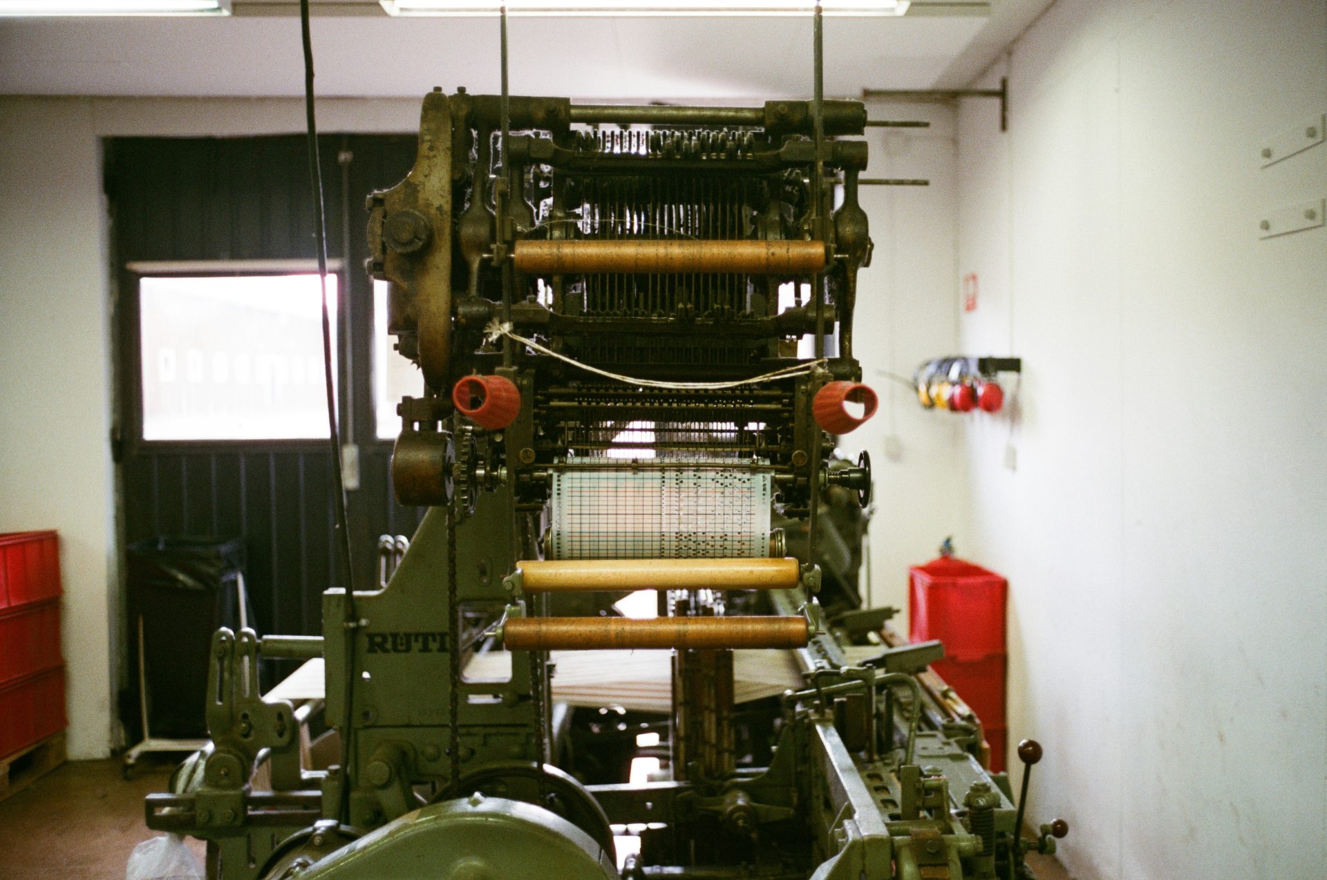 Industrial loom machine with threads and rollers.